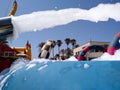 funny summer party launching white foam from a machine to a pool where people wearing swimsuit get wet against the hot of the sun Royalty Free Stock Photo