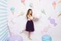 Funny surprised attractive young woman holding huge macaron on white background among ice cream. Happy sweet moments Royalty Free Stock Photo