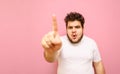 Funny surprised fat man with curly hair and beard looks and touches camera with shocked face on pink background. Overweight guy Royalty Free Stock Photo