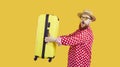 Funny surprised fat man going on summer holiday trip and carrying yellow suitcase Royalty Free Stock Photo