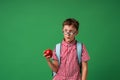 Funny, surprised schoolboy with glasses and holding Apple on green background Royalty Free Stock Photo