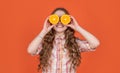 funny teen girl hold citric fruit on orange background