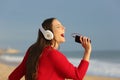 Funny teen singing and listening to music on the beach