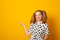 Funny teenage girl with a two-ponytail hairstyle looking sideways and pointing her index finger at copy space Royalty Free Stock Photo