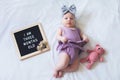 Funny three months old baby girl laying down on white background with letter board and teddy bear. Royalty Free Stock Photo