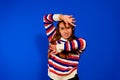 Funny Tiger. Portrait of cute playful little girl dressed in a striped sweater showing claws, blue studio background Royalty Free Stock Photo