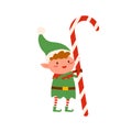 Funny tiny elf in green costume holding huge Christmas candy cane vector flat illustration. Cute Santa helper holding Royalty Free Stock Photo