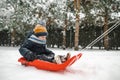 Funny toddler boy having fun with a sleigh in beautiful winter park. Cute child playing in a snow Royalty Free Stock Photo