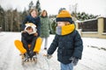 Funny toddler boy and his big sisters having fun with a sleigh in beautiful winter park. Cute child playing in a snow Royalty Free Stock Photo