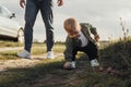 Funny Toddler Boy Playing with Toy Car Outdoors on the Country Road, Father Stepping Behind Him Royalty Free Stock Photo