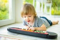 Funny toddler boy playing toy piano at home. Little boy learning to play piano. Child listening to music. Early development for Royalty Free Stock Photo