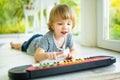 Funny toddler boy playing toy piano at home. Little boy learning to play piano. Child listening to music. Early development for Royalty Free Stock Photo