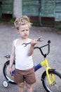 Funny toddler boy repairing his broken bike. Childhood.Cycling