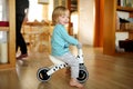 Funny toddler boy riding a baby scooter at home. Kid training balance on mini bike indoors Royalty Free Stock Photo