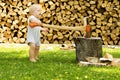 Funny toddler cutting firewoods with a huge axe