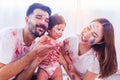 Funny toddler girl get stain color by put to faces and body with happy family, laughing together. Caucasian father and Asian