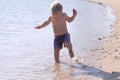 Funny toddler running in the sea. Cute baby boy has fun on vacations Royalty Free Stock Photo