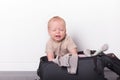 Funny toddler sitting in the suitcase and trying to pack it. Cute baby boy going to vacation Royalty Free Stock Photo