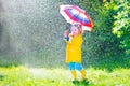 Funny toddler with umbrella playing in the rain