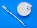 White shape of the tooth smiles at the jar of powder toothbrush on a blue background. The view from the top. Flat lay