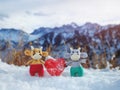 Funny toy bulls stand in a snowdrift in winter in the mountains and hold a heart in their paws