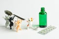 Funny toy kittens carry a teaspoon to an open green bottle with medicinal syrup. Game concept for accustoming children to the use Royalty Free Stock Photo