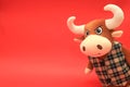 Funny toy orange bull on a red background. Beautiful bull with big white horns