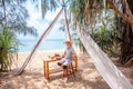 Funny travel man in straw hat sitting on beach restaurant with sea view