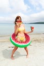 Funny travel woman in swimsuit posing with lifebuoy watermelon slice at paradise beach sea resort