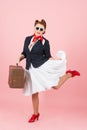 Funny traveler girl with suitcase and black sunglasses. Brunette woman in pin-up style with vintage case.