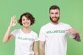 Funny two young friends couple in white volunteer t-shirt isolated on pastel green background studio portrait. Voluntary