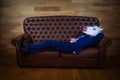 Funny unicorn in elegant suit lies on leather sofa