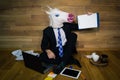 Funny unicorn in a suit and tie smiles and shows a white empty sheet with copy space.