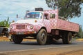 funny and unusual pink glamorous checkered truck transporting goods on the road. Vintage pink truck in Africa