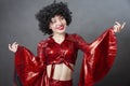 Funny vintage woman in afro wig and disco costume on a gray background