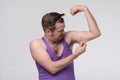 Funny weak sportsman exercising looking on his biceps