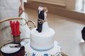 Funny wedding cake topper, figurines of bride and groom tied together with a rope, fun wedding moment with delicious white cake Royalty Free Stock Photo