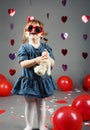 funny white Caucasian little girl toddler in studio with red balloons hearts on grey background wearing funny glasses Royalty Free Stock Photo