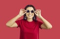 Funny woman in cool sunglasses on red studio background Royalty Free Stock Photo