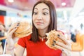 Funny woman eating hamburger inside in fast-food restaurant