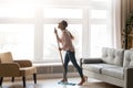 Funny woman holding mop microphone singing cleaning in living room Royalty Free Stock Photo