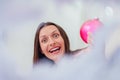 Funny woman looking childish and playful, holding pink bauble.