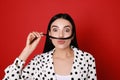 Funny woman making fake mustache with her hair on red background