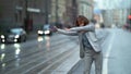 Funny woman with neck brace is dancing cheerfully on tram stop in city, fun and joke