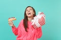 Funny woman in pink sweater looking up, hold eclair cake, red striped present box with gift ribbon isolated on blue Royalty Free Stock Photo