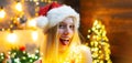 Funny woman in Santa hat on christmas background. Close up portrait of sexy girl flirting, show tongue. Face of young Royalty Free Stock Photo