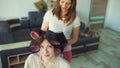 Funny woman smile while her girlfrind make fun curler hairstyle