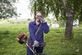 A woman stands with a hand trimmer for mowing grass