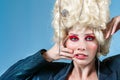 Funny woman wearing wig and makeup in blue studio Royalty Free Stock Photo