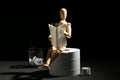 Funny wooden mannequin sitting on roll of toilet paper and reading magazine against dark background